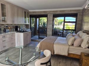 a bedroom with a large bed and a glass table at Somerset Garden Studio in Somerset West