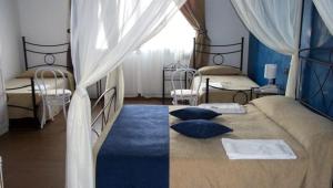 a bedroom with two beds with curtains and blue pillows at Hotel Noto Marina Scirocco & SPA in Noto Marina