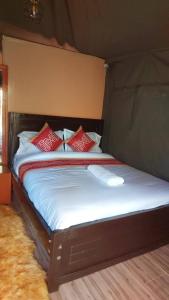 a bed in a tent with red pillows on it at Njukiini Forest Lodge in Embu