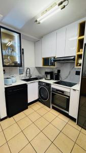 a kitchen with white cabinets and a washer and a dishwasher at The Urban Nest in Nelspruit