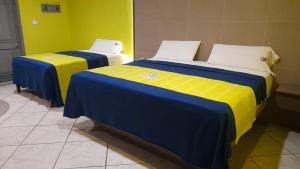 two beds with blue and yellow sheets in a room at Autohotel Punto de Descanso Cordoba in Córdoba