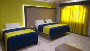 two beds in a room with yellow and blue at Autohotel Punto de Descanso Cordoba in Córdoba