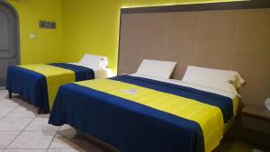 two beds with blue and yellow sheets in a room at Autohotel Punto de Descanso Cordoba in Córdoba