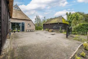 an old barn with a thatched roof and a driveway at Hoeve 1650 in Koekange