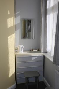 a bathroom with a sink and a mirror and a stool at Sandpiper Inn B&B and Pub in Ilfracombe