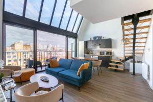 a living room with a blue couch and a kitchen at L'Escapade Paris in Le Kremlin-Bicêtre