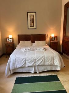 a bedroom with a large white bed with a green rug at La Casona de Blanca in Balcarce