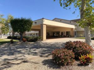 a large building with trees and flowers in front of it at Inn of Lompoc in Lompoc +7 photos