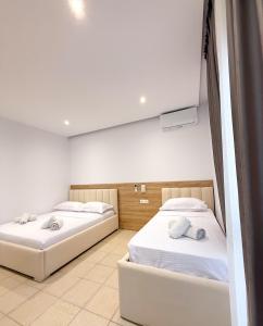 two beds in a room with white walls at Hotel Margjokaj2 Velipoje in Velipojë