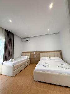 two beds in a room with white walls at Hotel Margjokaj2 Velipoje in Velipojë