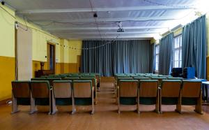 an empty room with green chairs and blue curtains at Rozulas skola in Rozula