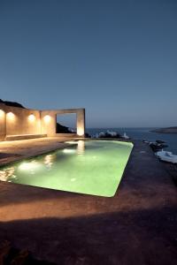 a swimming pool at night with the ocean in the background at Mykonos Dunes Villas in Mikonos