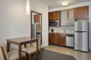 a kitchen with a table and a stainless steel refrigerator at Residence Inn by Marriott Orlando Downtown in Orlando