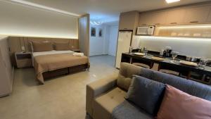 a room with a bed and a couch and a kitchen at Studio 48 - Lindo apto Studio no centro de Foz in Foz do Iguaçu