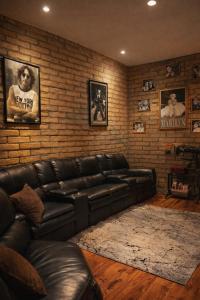a living room with a leather couch and a brick wall at Cabaña Santa Fe in Mesa de las Tablas