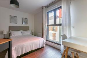 a bedroom with a bed and a desk and a window at L'Escapade Paris in Le Kremlin-Bicêtre
