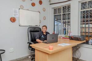 a woman sitting at a desk with a laptop at Phindulo Bed and Breakfast - No Loadshedding, Smart TVs & unlimited free fibre wifi in Krugersdorp +87 photos