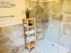 a bathroom with a shower with a wooden shelf at Chiemsee Beachhouse Apartment in Bernau am Chiemsee +25 photos