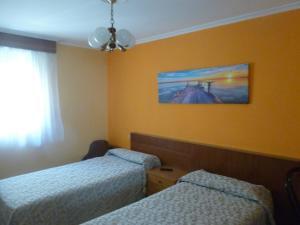 a room with two beds and a painting on the wall at Hostal O Choyo II in Ferrol