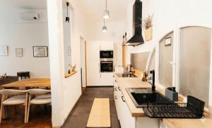 a kitchen with white cabinets and a wooden table at L'Arco Trieste studio living 1 in Trieste