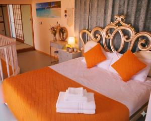 a bedroom with a large bed with orange and white pillows at 天然温泉付別荘in海友荘 in Shirahama