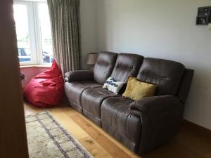 a brown leather couch with pillows in a living room at Hunthill in Tulach an Iarainn