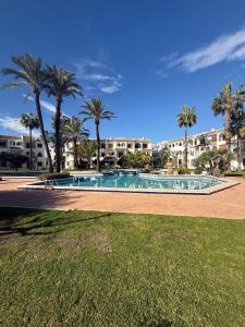 a swimming pool with palm trees and buildings in the background at Club aldeas de taray in San Javier