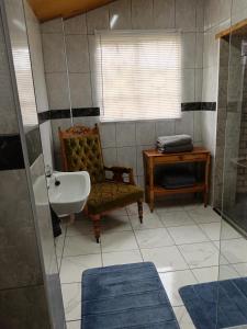 a bathroom with a sink and a chair and a mirror at IVCA Cottage in Addo