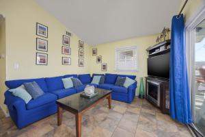 a living room with a blue couch and a tv at 7039 - A Wave From It All in Rodanthe