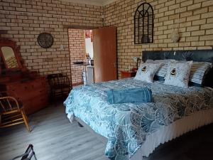 a bedroom with a bed with a blue comforter at IVCA Cottage in Addo