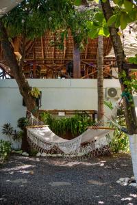a hammock hanging from two trees in front of a building at The Beach Break Hotel El Zonte in El Zonte