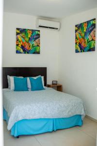 a bedroom with a bed with blue pillows at The Beach Break Hotel El Zonte in El Zonte