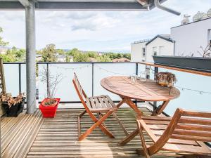 a wooden table and chairs on a balcony at Appartement lumineux proche Genève et Jura 3 chambres, terrasses et parking in Gex