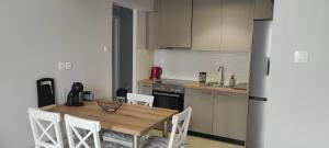 a kitchen with a wooden table and white chairs at Parastaseis City Flat Central in Patra
