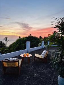 a patio with a table and chairs and a sunset at Celestine's Hideaway in Kamburugamuwa