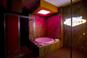a bathroom with a pink tub and a neon sign at COSMOPOLITAN Autohotel in Boca del Río
