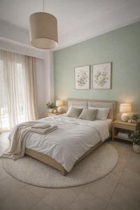 a white bedroom with a large bed with a rug at Midway Point Apts in Heraklio