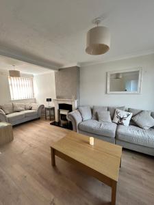 a living room with two couches and a table at Cosy stylish house West Hull in Hull