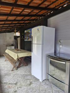 a white refrigerator in a kitchen with a table at Wood house casa privada in Abraão