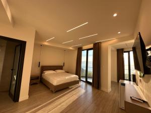 a bedroom with a bed and a tv and some windows at Hotel Gramozi in Kaninë