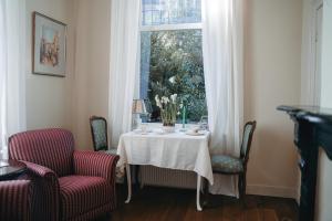 a table with a white table cloth and chairs and a window at B&B Chez Nous in Geesteren