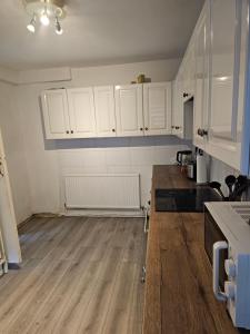 a kitchen with white cabinets and a wooden floor at M4 Victoria Hub in Newport +60 photos