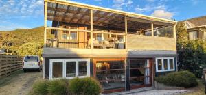 a house with a balcony with a table and chairs at Beachfront Sunset Bach in Piha