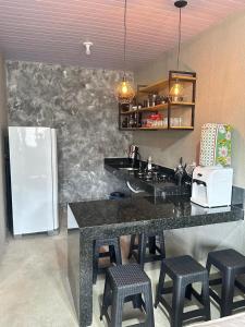 a kitchen with a counter with stools and a refrigerator at Chalé 1 - próximo à igreja do céu in Viçosa do Ceará