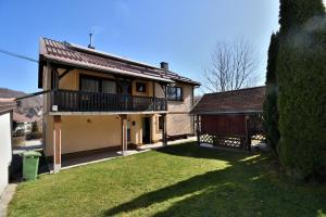 a house with a balcony and a yard at Apartment Tadey in Fužine