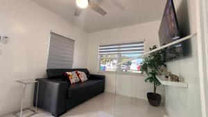 a living room with a black couch and a window at Comfortable modern apartment- central location. in Miami