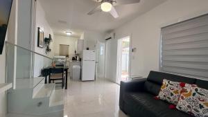 a living room with a black couch and a kitchen at Comfortable modern apartment- central location. in Miami