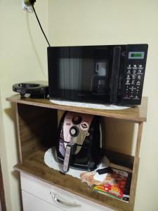 a microwave sitting on top of a wooden shelf at Suites da Gladys in Foz do Iguaçu