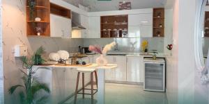 a kitchen with white cabinets and a bar with stools at شاليه روجا Roja Chalet in As Sulayf