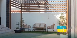 a pergola with chairs and a table on a patio at شاليه روجا Roja Chalet in As Sulayf